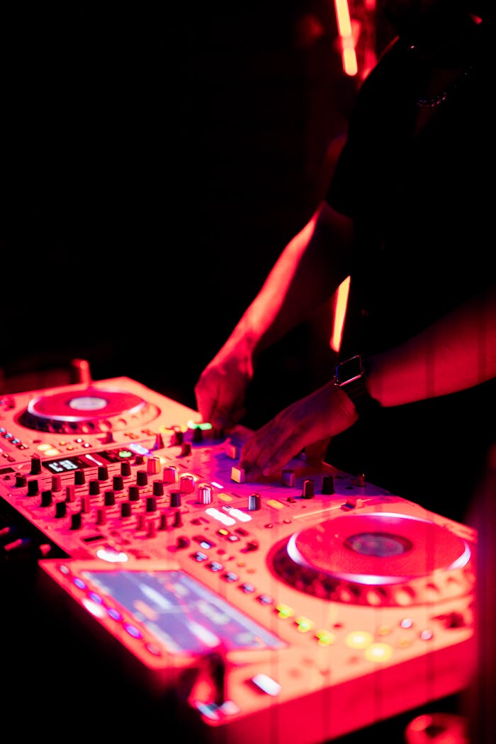 DJ spinning at a nightclub with vibrant red lighting and dynamic sound mixers.